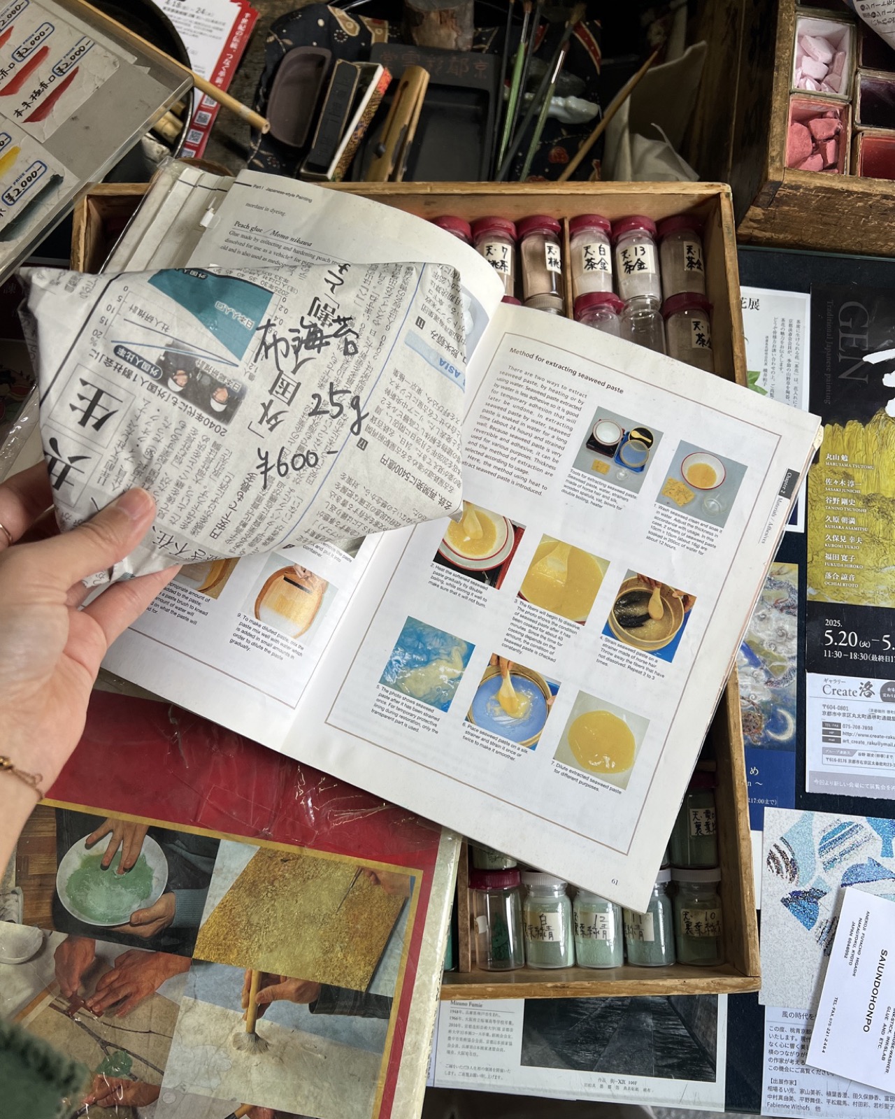 Funori wrapped in newspaper next to a reference book page on extracting seaweed paste